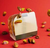 Pistachios falling from the sky onto packaging against red background photo