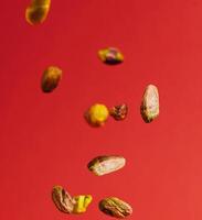Pistachios falling down on red background photo