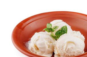 Three scoops of vanilla ice cream melting in rustic bowl with mint garnish photo