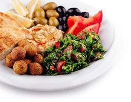 Plate presenting a colorful and tasty middle eastern mezze platter with various dips and salads photo