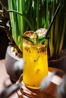 Refreshing passion fruit lemonade with ice and mint on wooden table photo