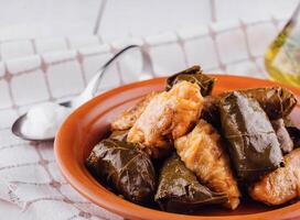 Traditional dolma stuffed grape leaves with rice and spices on rustic table setting photo