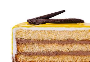 Delicious piece of cake with yellow icing and chocolate decoration isolated on white background photo