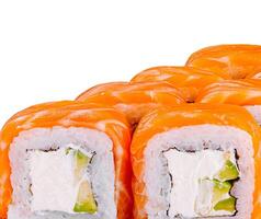 Philadelphia sushi rolls covered with salmon slices are lying in a row on white background photo