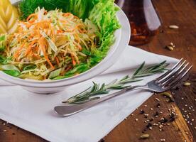 Fresh cabbage salad with apple slices and herbs on wooden table photo