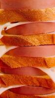 Slices of bread and sausage creating delicious multi layered sandwich photo
