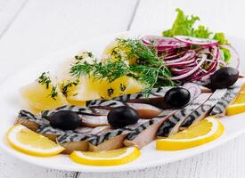 Sliced salted mackerel with potatoes and onions on white plate photo