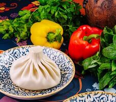 Traditional georgian dish khinkali lying on a plate with herbs and vegetables in the background photo
