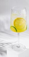 Glass of refreshing lemonade with lemon and lime slices on white background photo