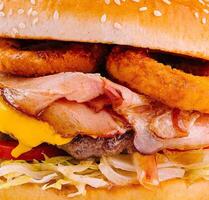 Delicious bacon and onion rings cheeseburger close up photo