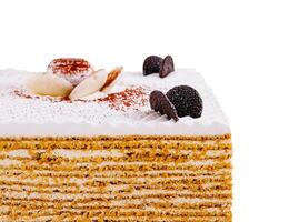 Delicious multi layered honey cake decorated with chocolate and white cream standing on white background photo