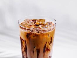 Iced coffee with chocolate syrup drizzled on the glass standing on white background photo