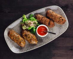 Traditional lula kebab on a plate with tomato sauce and salad photo