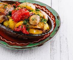 Delicious roasted vegetables and chicken breast served in rustic clay pot photo