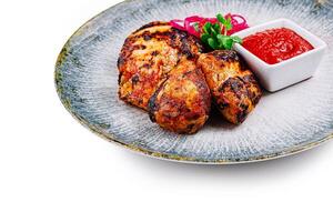 Grilled chicken on plate with red sauce and onions photo