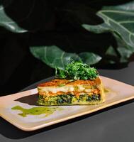 Delicious slice of quiche with salmon and spinach resting on plate photo