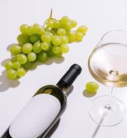 Bottle of white wine lying down with a glass of wine and green grapes photo