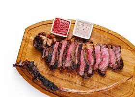 Sliced grilled tomahawk steak resting on wooden cutting board photo