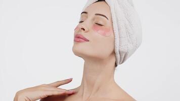 Close-up of a young woman with under-eye patches targeting wrinkles and dark circles. Isolated against a white background, this image emphasizes skincare and the fight against signs of fatigue video
