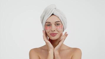 Close-up of a young woman with under-eye patches targeting wrinkles and dark circles. Isolated against a white background, this image emphasizes skincare and the fight against signs of fatigue video
