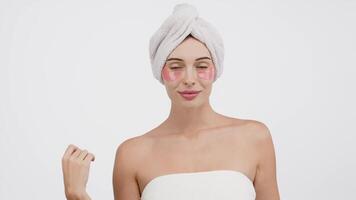 Close-up of a young woman with under-eye patches targeting wrinkles and dark circles. Isolated against a white background, this image emphasizes skincare and the fight against signs of fatigue video