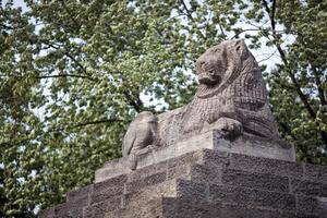 Stone Lion Statue at the Berlin Zoo Entrance Surrounded by Greenery photo