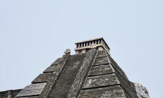 Gray rock stone pyramid styled building structure exterior isolated on horizontal ratio plain sky background. photo