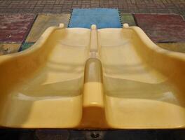 Empty playground yellow plastic double slide toy isolated on horizontal ratio outdoor environment background. photo