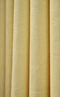 Yellow colored curtain fabric texture isolated on vertical ratio background. photo