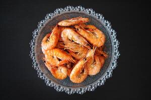 Cooked shrimp in a glass bowl on a black background. photo