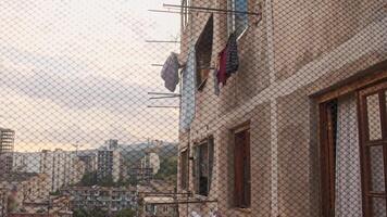 Through the fence grating, you can see how laundry is being dried on ropes stretched in the courtyard of an old multi-storey Soviet-style house. video