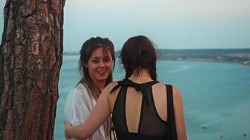 Two young women communicate and provide mutual support during their trip, after which they take photographs together using a mobile device. video