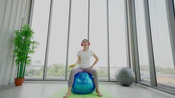 A woman is sitting on an exercise ball in a room video