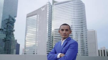 A confident businessman in a blue suit stands with arms crossed on a rooftop, with skyscrapers in the background. The image conveys leadership, ambition, and corporate success in an urban environment. video
