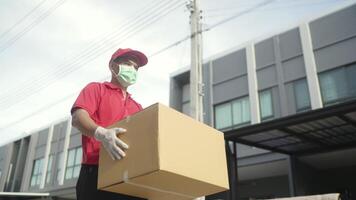 A man in a red shirt and mask is carrying a box video