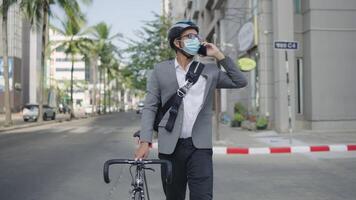 A man in a suit and mask is walking down the street with a bicycle video