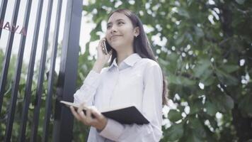 A woman talking on the phone while standing in front of a fence video