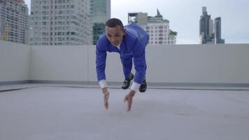 A businessman in a blue suit performs push-ups on a rooftop, showcasing physical fitness, determination, and resilience. The scene blends corporate attire with exercise strength and perseverance. video