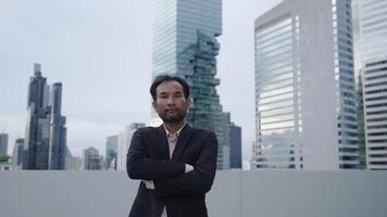 A confident businessman stands with arms crossed on a rooftop, with towering skyscrapers in the background. The image exudes leadership, ambition, and corporate success in an urban environment. video