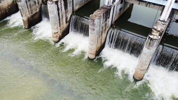 represa Desbordamiento aéreo ver de un represa desbordante con agua, demostración el fuerza y poder de naturaleza. el imagen capturas el intrincado detalle de el hormigón estructura y el arremolinándose agua video