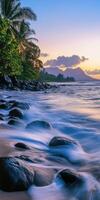 Beautiful tropical beach at dusk with waves gently lapping on rocks photo