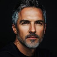 Handsome man with gray hair posing against a dark background photo