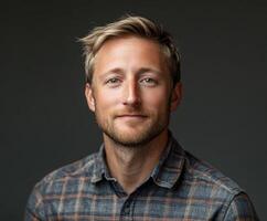 Portrait of a smiling man in a flannel shirt against a dark background photo