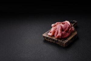 A pieces of raw fresh pork on a wooden cutting board with spices and herbs photo