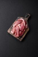 A pieces of raw fresh pork on a wooden cutting board with spices and herbs photo