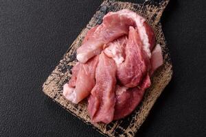 A pieces of raw fresh pork on a wooden cutting board with spices and herbs photo