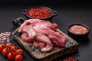 A pieces of raw fresh pork on a wooden cutting board with spices and herbs photo