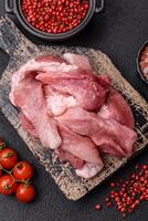 A pieces of raw fresh pork on a wooden cutting board with spices and herbs photo