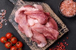 A pieces of raw fresh pork on a wooden cutting board with spices and herbs photo