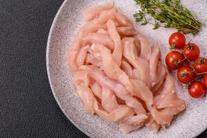 Raw chicken fillet cut into strips with spices and herbs photo